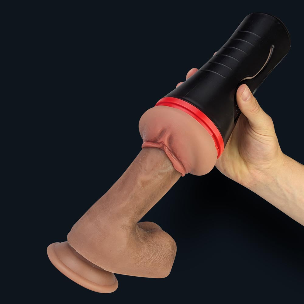 Masturbador masculino Lindsey en su estuche metido en un dildo sostenido en una mano, demostración de uso